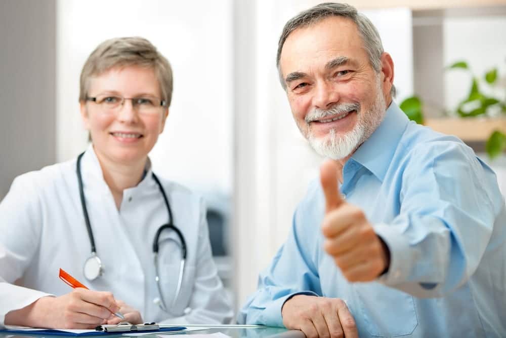 Man smiling and giving the thumbs up in meeting with doctor