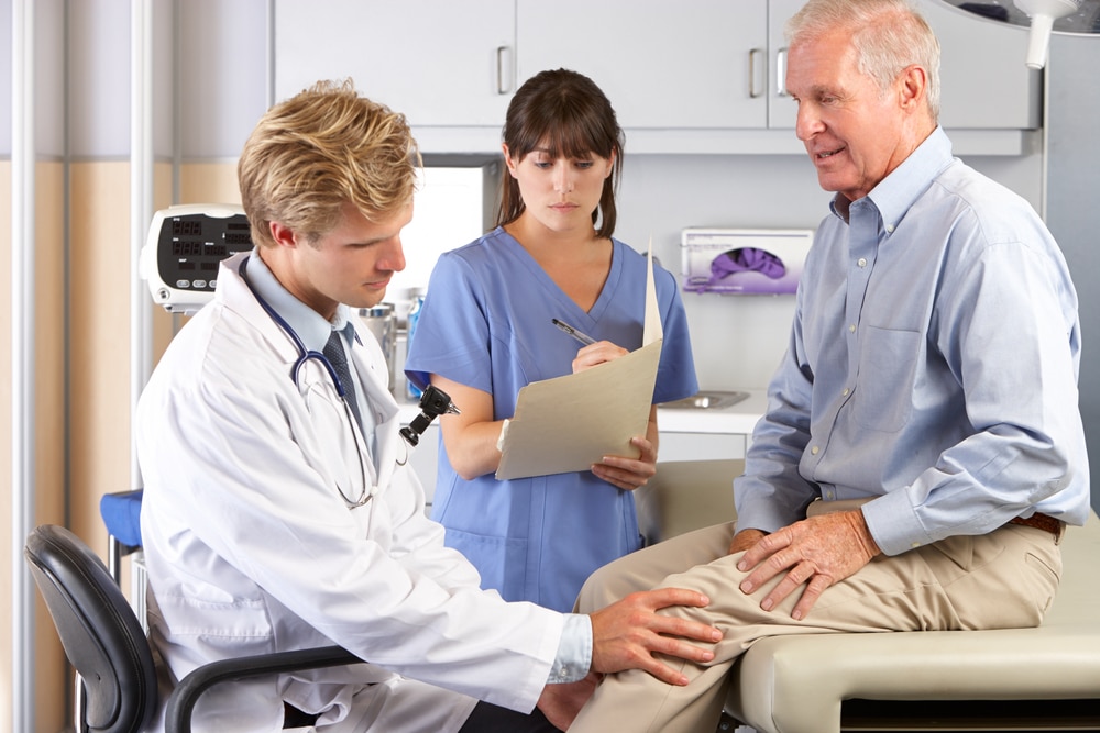 Doctor examining the knee of an older male patient, article covers the topic "Does Medicare Cover Coolief Knee Treatment"
